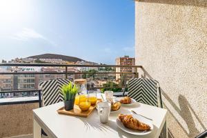 a table with food and orange juice on a balcony at Valdes Center Los Cristianos in Los Cristianos