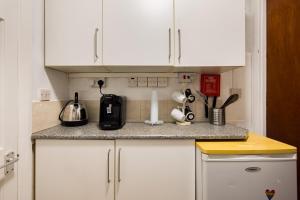 uma cozinha com armários brancos e uma bancada em 1BD Apartment near Olympic Park, East London em Londres