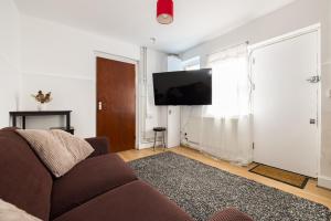 sala de estar con sofá y TV de pantalla plana en 1BD Apartment near Olympic Park, East London en Londres