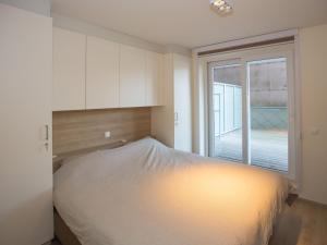 uma cama num quarto com uma grande janela em Riva spacious and modern with top location em Middelkerke