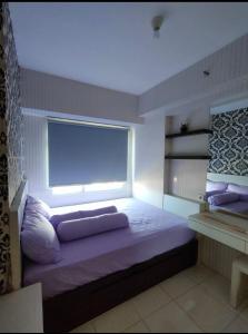 Schlafzimmer mit einem großen Bett und einem Fenster in der Unterkunft Apartemen Pakuwon Educity yale in Surabaya