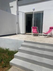 two pink chairs sitting on a patio next to a building at Logement entier et indépendant D in Rabat