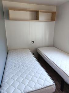 two beds in a small room with white walls at Mobilhomes Quiberon Camping Conguel - Bord de Mer in Quiberon