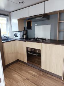 a kitchen with wooden cabinets and a stove top oven at Mobilhomes Quiberon Camping Conguel - Bord de Mer in Quiberon
