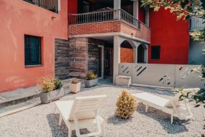eine Terrasse mit zwei weißen Stühlen und einem roten Gebäude in der Unterkunft Design & Giardino con Sauna & Hammam - Free WiFi in Margarita