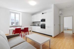 een witte woonkamer met een bank en een tafel bij Greta House in Colico