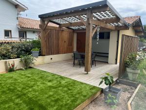 uma pérgola de madeira com uma mesa num quintal em Sun studio em Capbreton