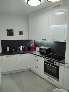 a kitchen with white cabinets and a black counter top at Apartamenty POSNANIA - MALTA , Faktura VAT, bezkontaktowe zameldowanie, bezpłatne miejsce parkingowe in Poznań