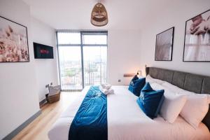 a bedroom with a large white bed with blue pillows at Pluxa Nordic Sky - Spacious Manchester Gem 2Bed 2bath, & free parking in Manchester