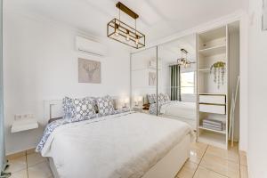 a white bedroom with a large bed and a mirror at Ramada Costa Adeje Apartment in Adeje +45 photos