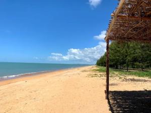 a beach with a straw umbrella and the ocean at Casa Marfim - Privacidade, charme e conforto à 50m do rio in Caravellas +14 photos