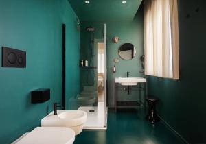 a green bathroom with a toilet and a sink at Re Versiliana Hotel in Marina di Pietrasanta