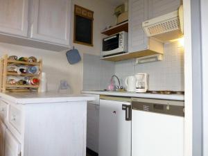 eine kleine Küche mit weißen Schränken und einer Mikrowelle in der Unterkunft Appartement Huez, 2 pièces, 4 personnes - FR-1-405-140 in L'Alpe-d'Huez