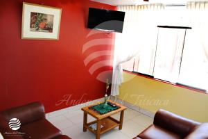プーノにあるANDENES DEL TITICACAの赤い壁のリビングルーム(テーブルの上にランプ付)