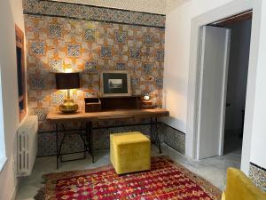 Cette chambre comprend un bureau avec une télévision et un tabouret jaune. dans l'établissement Maison typique de la médina, à Tunis