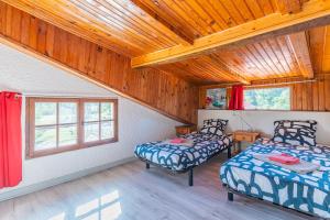 2 Betten in einem Zimmer mit Holzdecken und Fenstern in der Unterkunft Duplex en residence tennis piscine in Naujac-sur-Mer