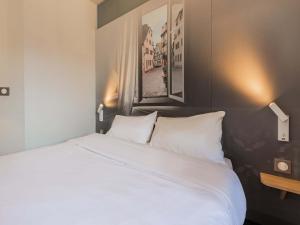 a bedroom with a large bed with white pillows at B&B HOTEL Strasbourg Sud Ostwald in Ostwald