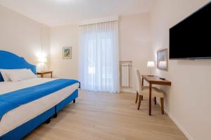 een slaapkamer met een bed, een bureau en een televisie bij Gemma di Zagara Apartment in Sorrento