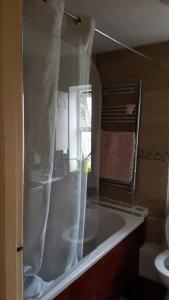 a bathroom with a tub with a shower curtain at An oasis of calm next to M'cr City Centre + Parking in Manchester