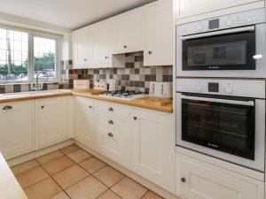 a white kitchen with white cabinets and appliances at 1 Tan Yr Ywen in Conwy