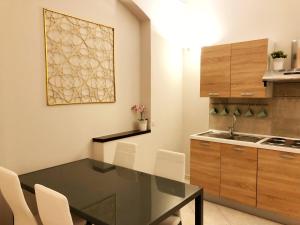 una cucina con tavolo nero e sedie bianche di La Borasca - Apartments a Casalpusterlengo