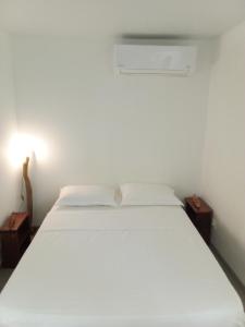 uma cama branca num quarto com duas mesas de cabeceira em Bungalow de charme em Montjoly