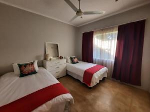 a bedroom with two beds and a dresser and a window at Leadwood Lodge in Tzaneen
