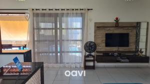a living room with a large window and a television at Qavi - Casa Tropical #ParaísoDoBrasil in Touros