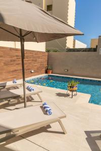 an umbrella and a chair next to a swimming pool at 49 Sunrise Lodge in Għajnsielem