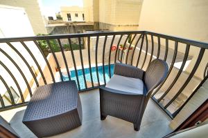 a balcony with two chairs and a swimming pool at 49 Sunrise Lodge in Għajnsielem