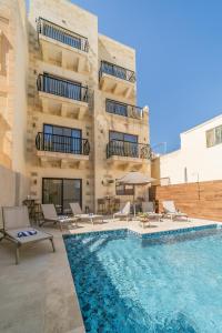 a hotel with a swimming pool with chairs and a building at 49 Sunrise Lodge in Għajnsielem