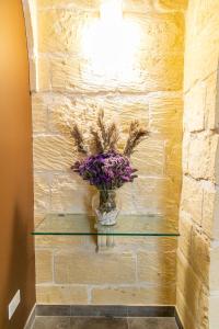a vase of flowers on a glass shelf on a brick wall at 49 Sunrise Lodge in Għajnsielem