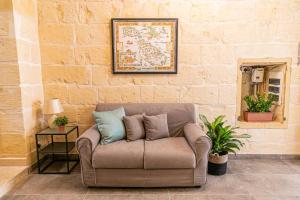 a couch with pillows sitting in a room with a brick wall at 49 Sunrise Lodge in Għajnsielem