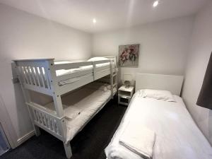 a small room with two bunk beds and a bed at Evergreen Lodge - Two Bed Lux Flat - Parking, Garden, Patio, WIFI, Netflix - Close to Blenheim Palace & Oxford - F3 in Kidlington