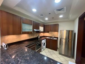 a kitchen with wooden cabinets and a stainless steel refrigerator at 2Bedroom Palm Jumeirah luxury Stay At Golden Mile 10 in Dubai