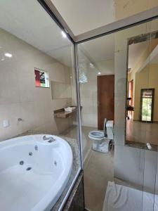 a bathroom with a bath tub and a toilet at Hotel Pousada Bambuzal in Sana