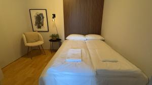 a large white bed in a room with a chair at North Estate Kræmervegen in Tromsø