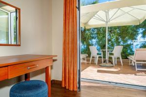 a room with a desk and a table with an umbrella at Hotel Dobrovit in Baška