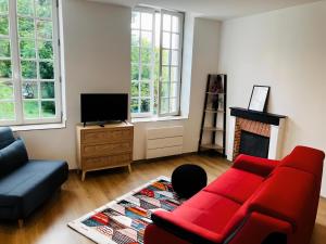sala de estar con sofá rojo y chimenea en La Grand Maison, en Orléans