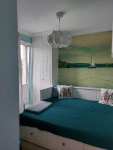 1 dormitorio con 1 cama con una pintura en la pared en Apartament MUSZELKA na Solnej 11 z garażem, en Kołobrzeg