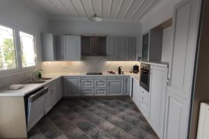 una gran cocina blanca con armarios y electrodomésticos blancos en Ευρύχωρη και φωτεινή κατοικία στη Ζάκυνθο en Makhairádhon