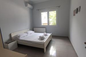 Habitación blanca con cama y ventana en Ευρύχωρη και φωτεινή κατοικία στη Ζάκυνθο en Makhairádhon