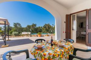 En el patio hay una mesa con una botella de vino. en Villa Fioralba, en Castrignano del Capo