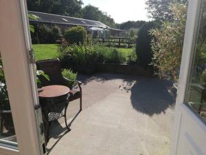 an open door to a patio with a table and a chair at Gables Farm, Self contained flat by Middlewood Way in Poynton