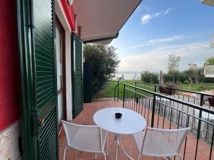 eine Terrasse mit einem weißen Tisch und Stühlen auf dem Balkon in der Unterkunft Hotel Saviola in Sirmione
