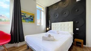 una camera con un letto bianco e una sedia rossa di Hotel Le Florian a Cannes