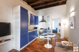 a kitchen with blue cabinets and a table with chairs at Nido Milanese - Bocconi, Navigli, Duomo in Milan