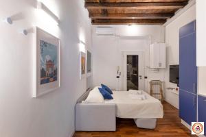 a white room with a bed with blue pillows on it at Nido Milanese - Bocconi, Navigli, Duomo in Milan