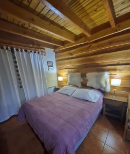 1 dormitorio con cama morada y techo de madera en Villa Cerro Catedral, excelente monambiente en San Carlos de Bariloche