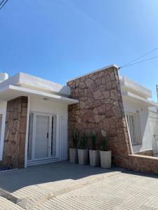 a white house with a stone wall at CASA ALQUILER TEMPORAL VILLA CABRERA in Córdoba